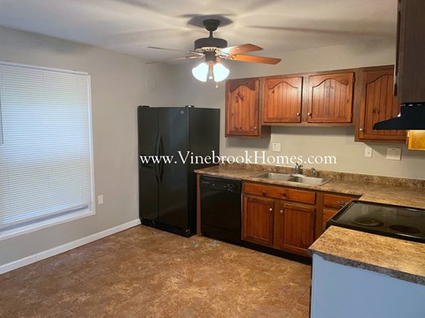 A kitchen with a black fridge and wooden cabinets.