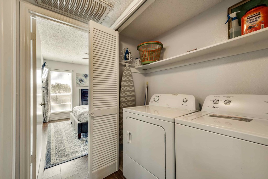 a washer and dryer in a laundry room with a door to a bedroom
