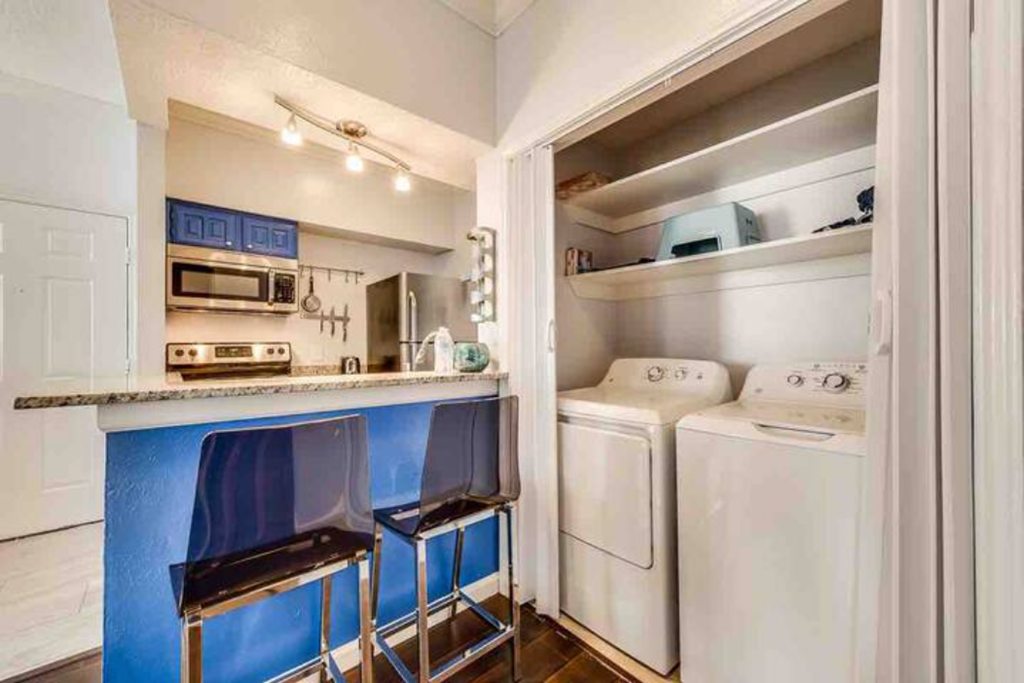a kitchen with a bar and stools and a washing machine