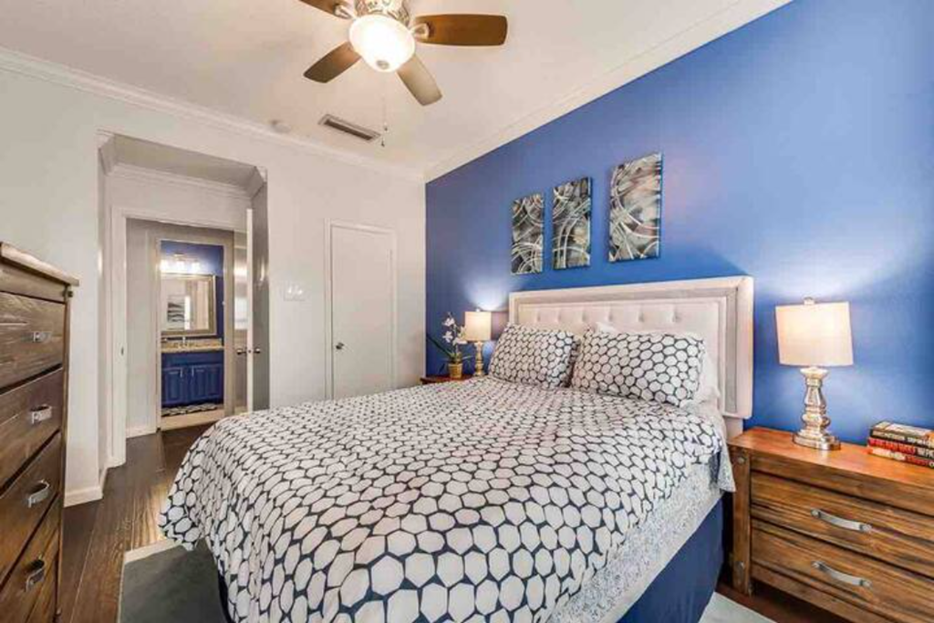 a blue and white bedroom with a bed and a ceiling fan