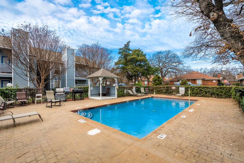 a swimming pool with chairs and a house in the background