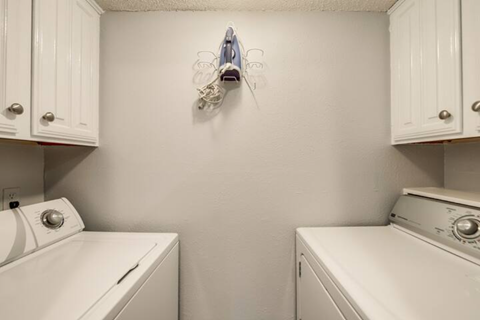 a white laundry room with white appliances and white cabinets