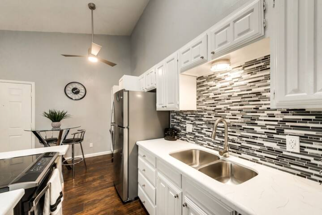 a kitchen with a sink and a stainless steel refrigerator