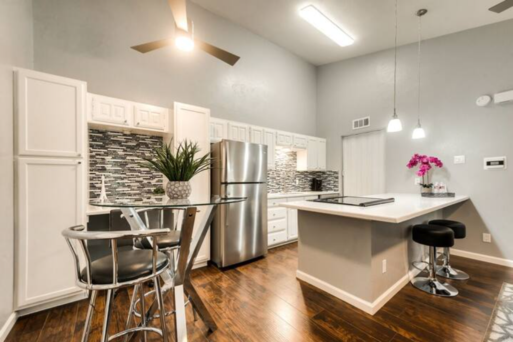 a kitchen with a bar and a stainless steel refrigerator