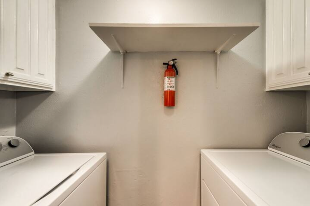 a white kitchen with a fire extinguisher on the wall