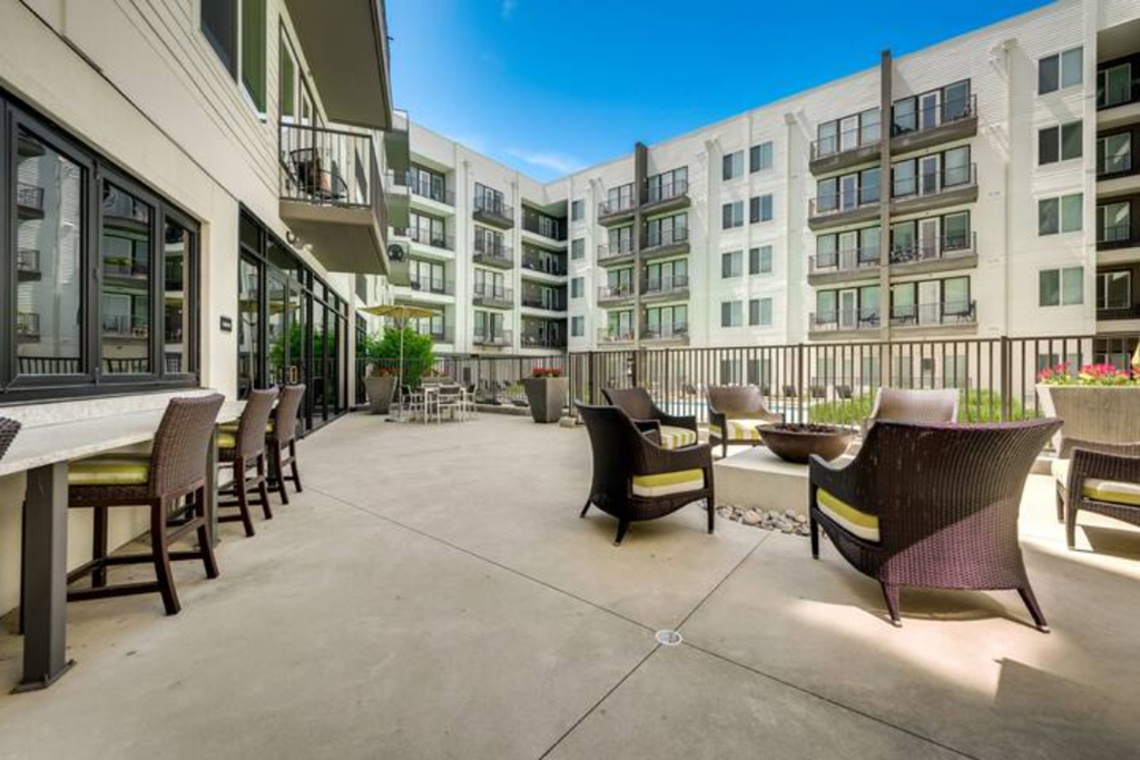 an outdoor patio with chairs and tables and an apartment building