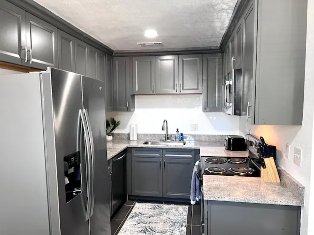 a kitchen with gray cabinets and a stainless steel refrigerator