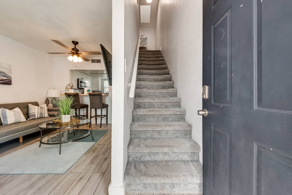 an open door looking into a living room with a staircase in front of it