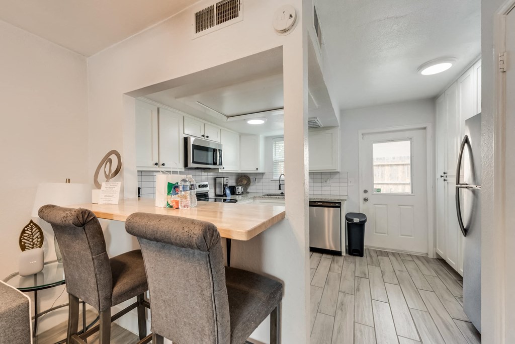 a kitchen with a bar and chairs and a refrigerator
