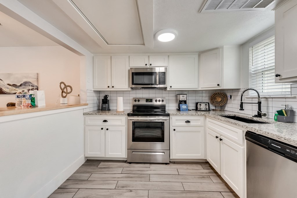 a kitchen with white cabinets and stainless steel appliances