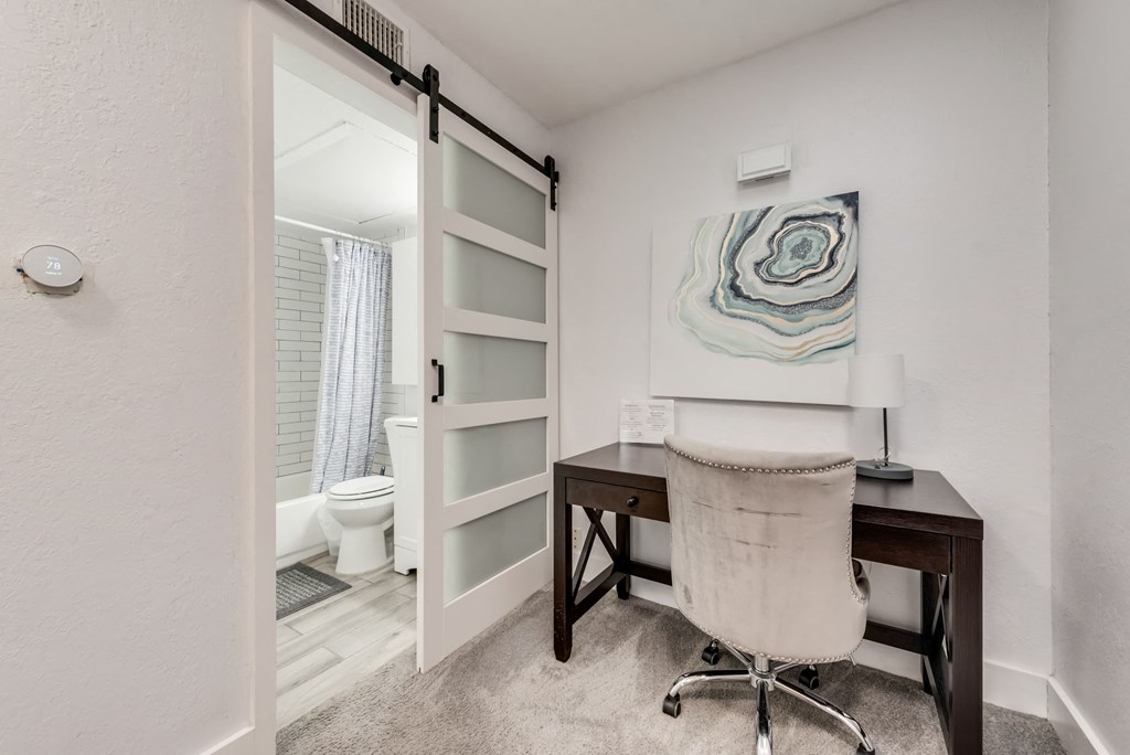 a home office with a desk and a bathroom with a toilet