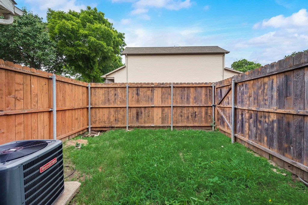 a wooden fence in a yard with a house in the background