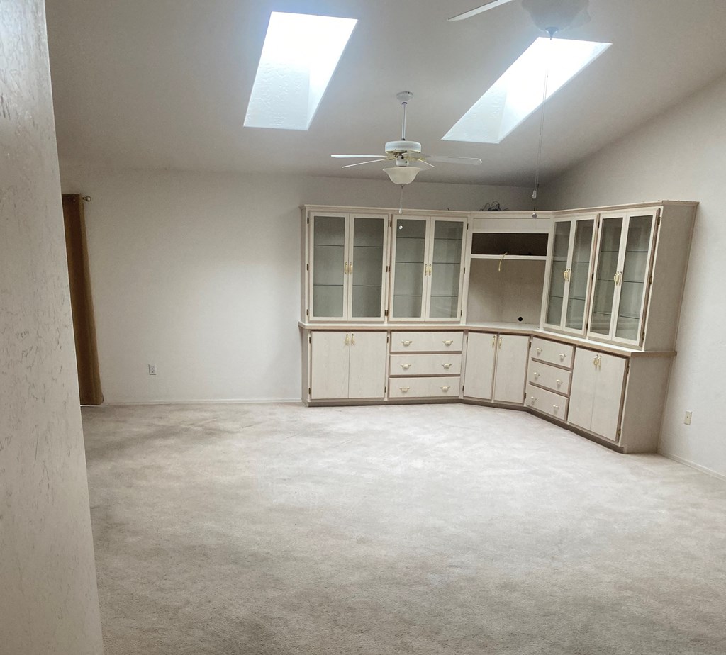 an empty room with white cabinets and a ceiling fan