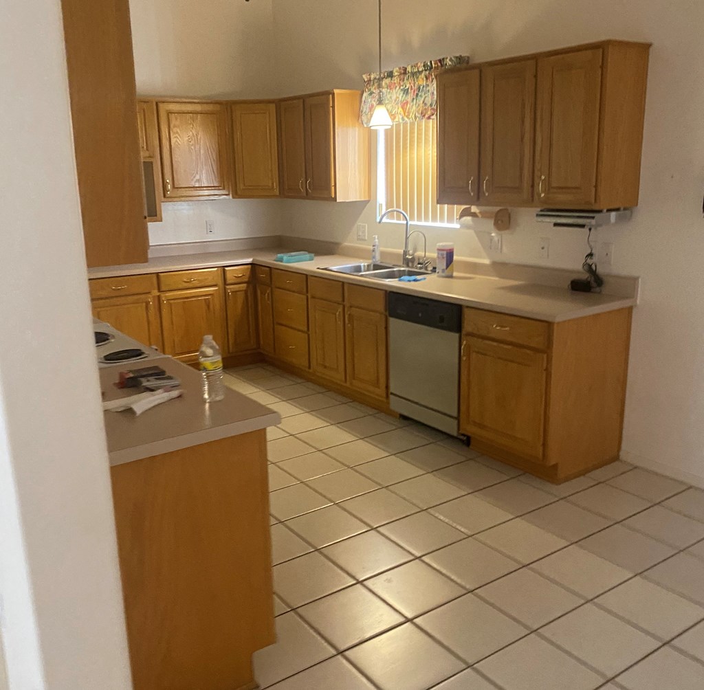 an empty kitchen with wooden cabinets and a white tiled floor