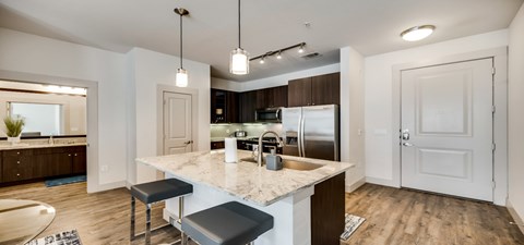 a kitchen with a marble counter top and a stainless steel refrigerator