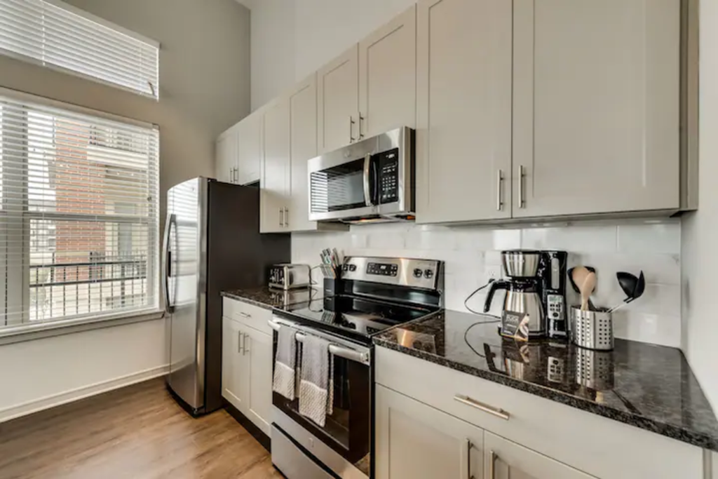 a kitchen with white cabinets and a black counter top