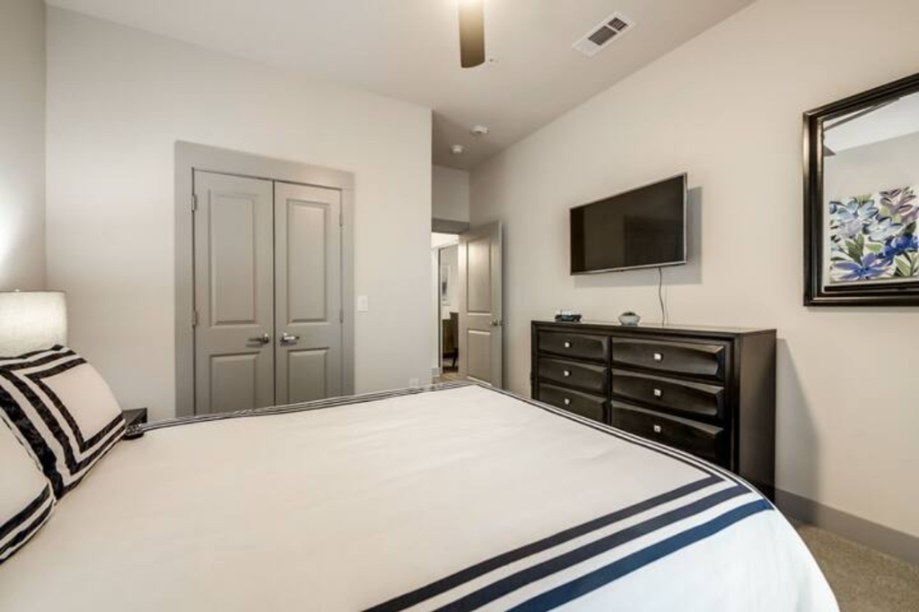 a white bedroom with a large bed and a tv