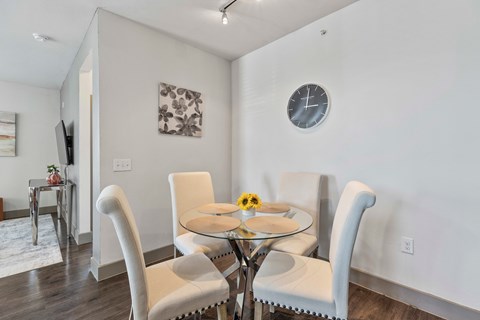 A dining room with a glass table and white chairs.