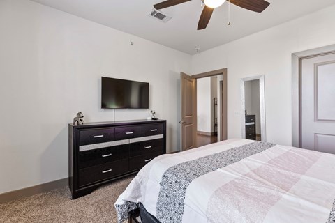 A bedroom with a bed, dresser, and television.