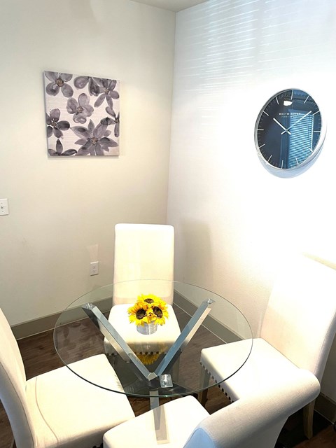 a living room with a glass table and a clock on the wall