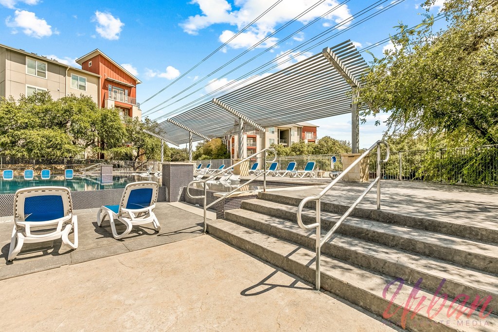 a pool with lounge chairs and stairs next to a pool