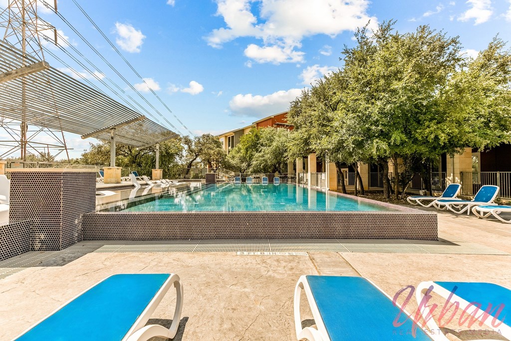 a swimming pool with lounge chairs and a building in the background