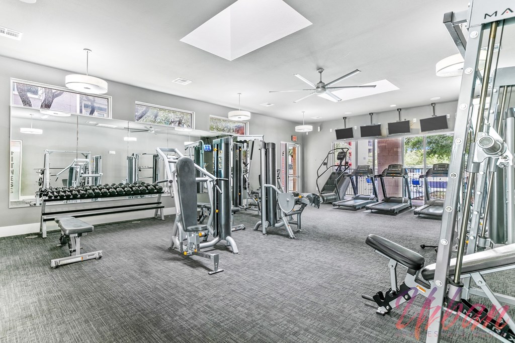 a gym with weights and cardio machines and a mirrored wall