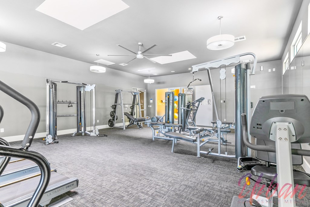 a gym with weights and cardio machines and a ceiling fan