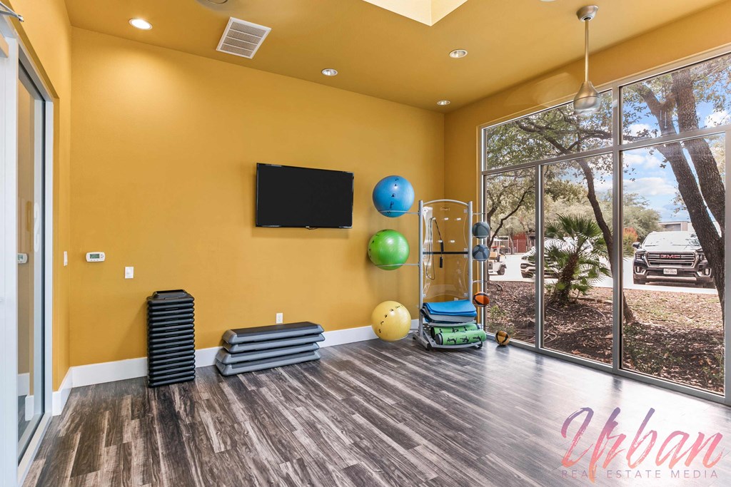 a workout room with a large window and a tv