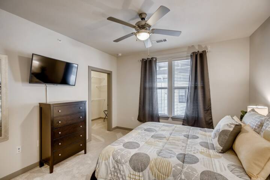 a bedroom with a bed and a ceiling fan and a tv