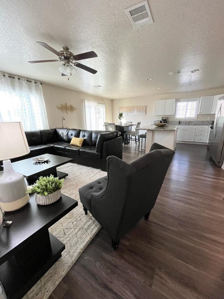 a living room with black furniture and a ceiling fan