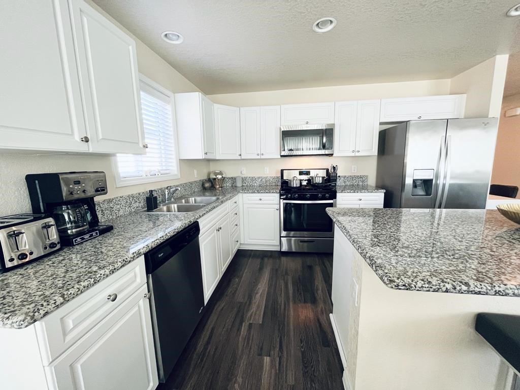 a kitchen with white cabinets and granite counter tops