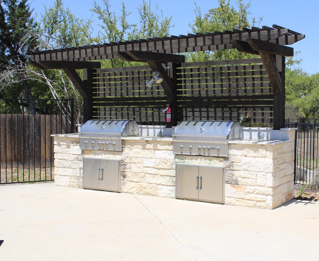 a stone outdoor kitchen with two islands and a wooden structure