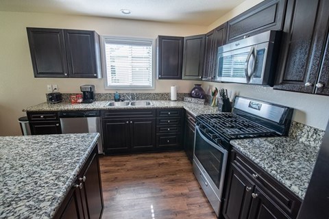 a kitchen with granite counter tops and black cabinets