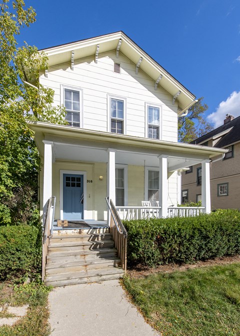 a white house with a porch and a blue door