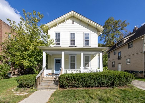 a small white house with a porch and a sidewalk