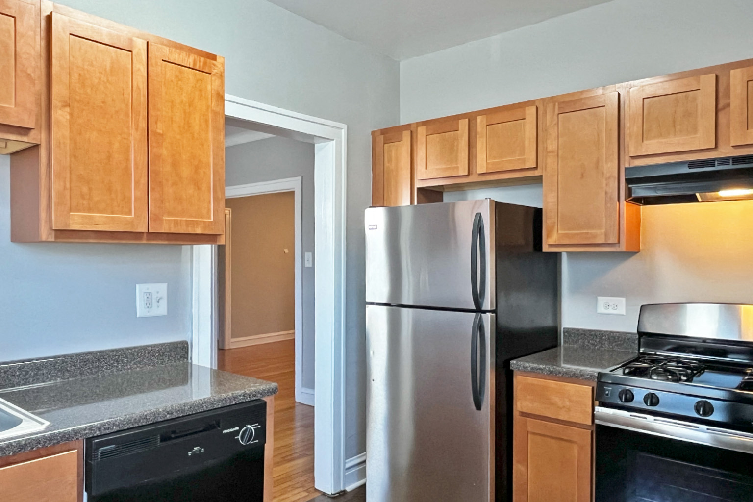 A kitchen with a stainless steel refrigerator and wooden cabinets.