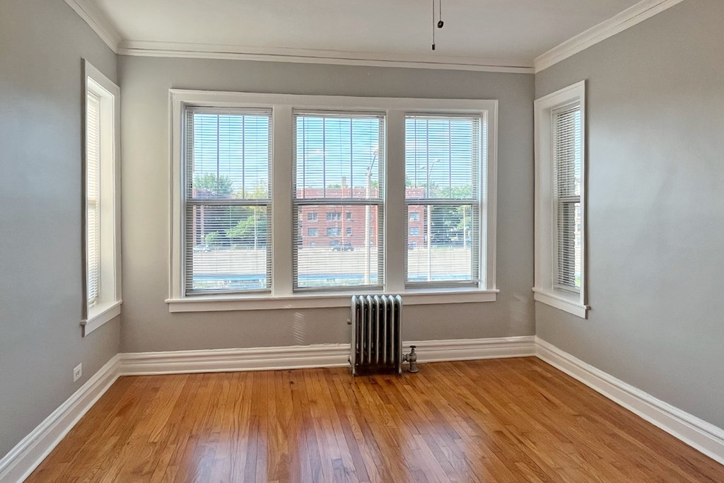 A room with wooden floors and three windows.