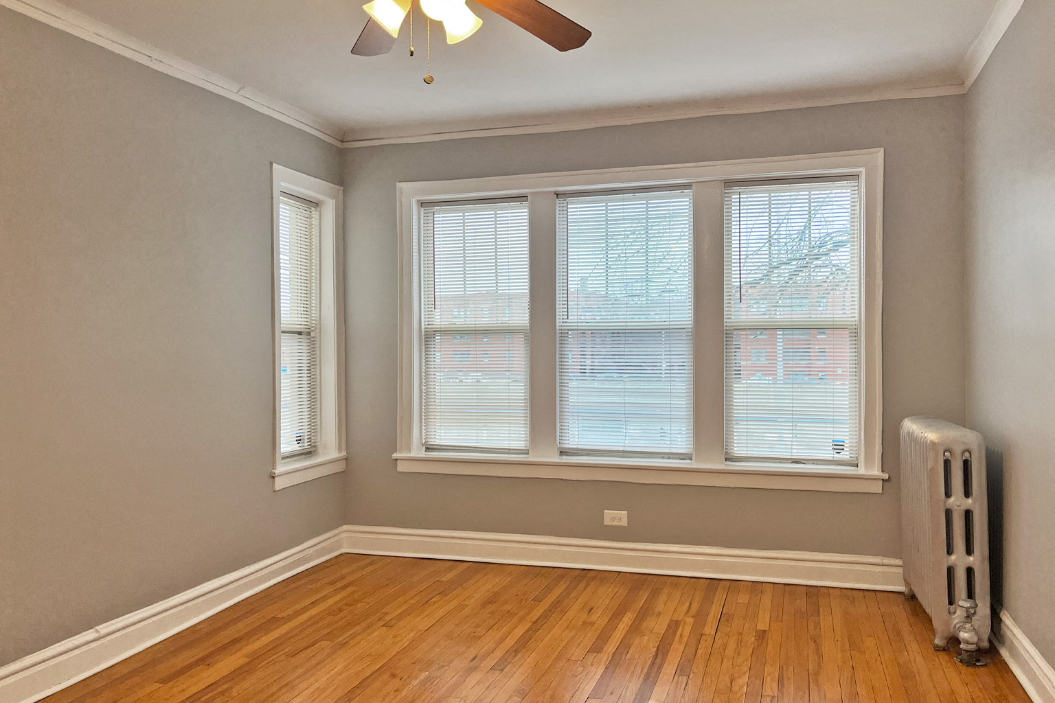 A room with a ceiling fan and a window with blinds.