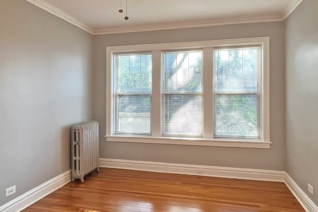 A room with a window and a radiator on the floor.