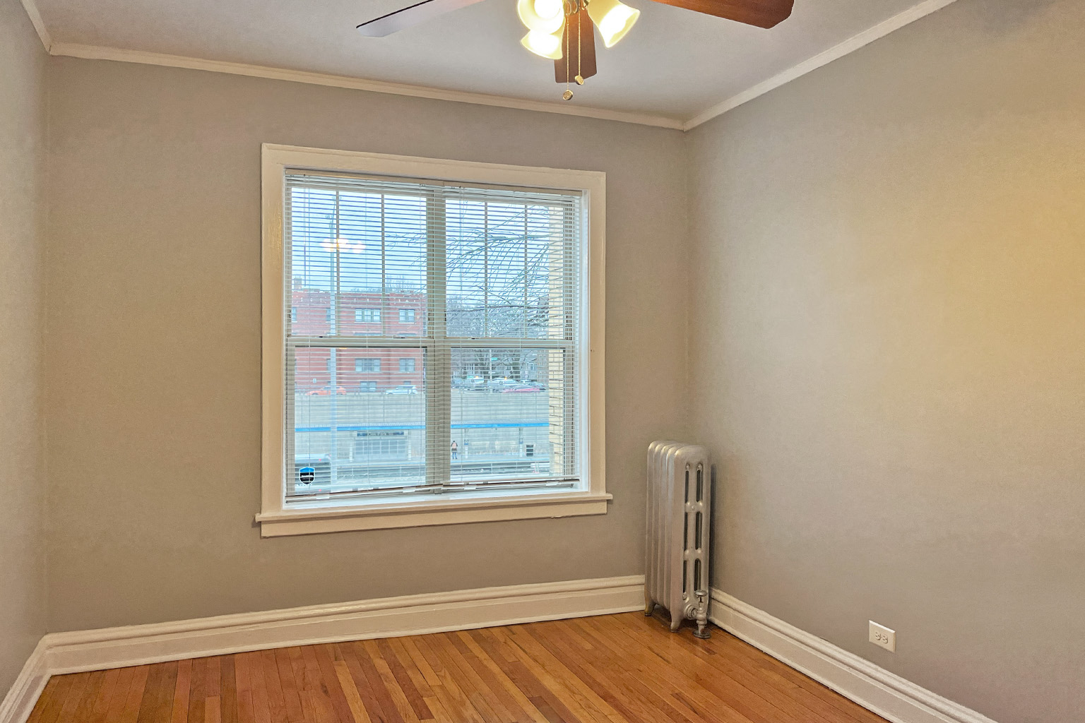 A room with a window and a fan on the ceiling.