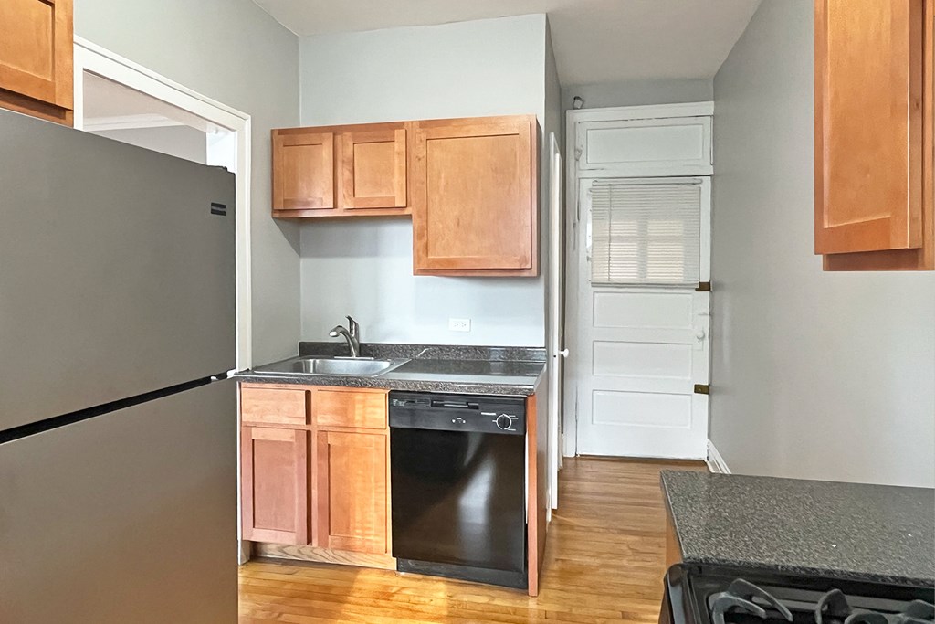 A kitchen with wooden cabinets and a black fridge.