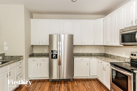 a kitchen with white cabinets and stainless steel refrigerator