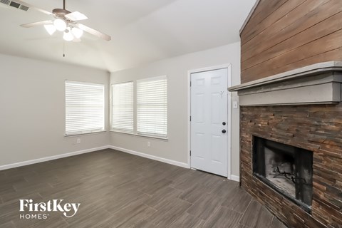a living room with a fireplace and wooden floors and a white door
