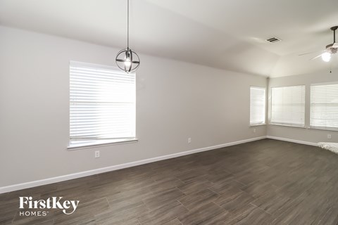 a living room with wood floors and white walls and a large window