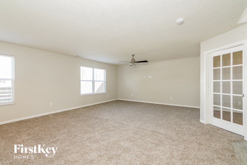 A spacious room with a ceiling fan and two windows.
