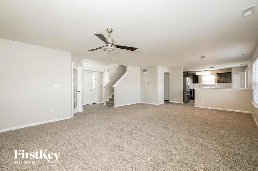 A spacious room with a carpeted floor and a ceiling fan.