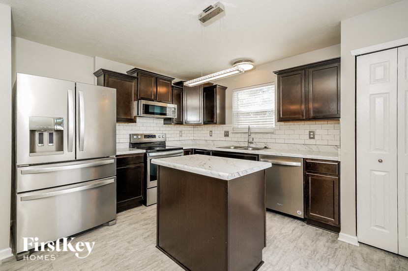 A kitchen with a stainless steel refrigerator and a white door.