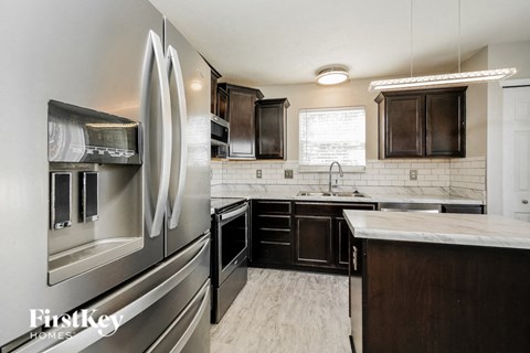 A modern kitchen with a stainless steel refrigerator and black cabinets.