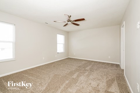 A room with a carpet floor and a ceiling fan.